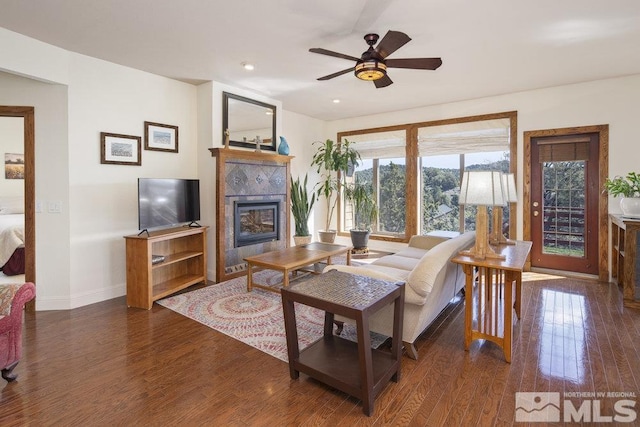 living area with baseboards, wood finished floors, a tile fireplace, and ceiling fan
