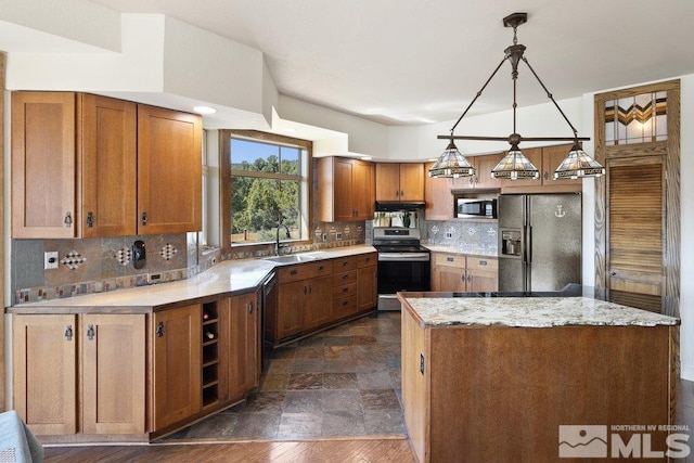 kitchen with brown cabinets, decorative backsplash, a center island, stone finish floor, and appliances with stainless steel finishes