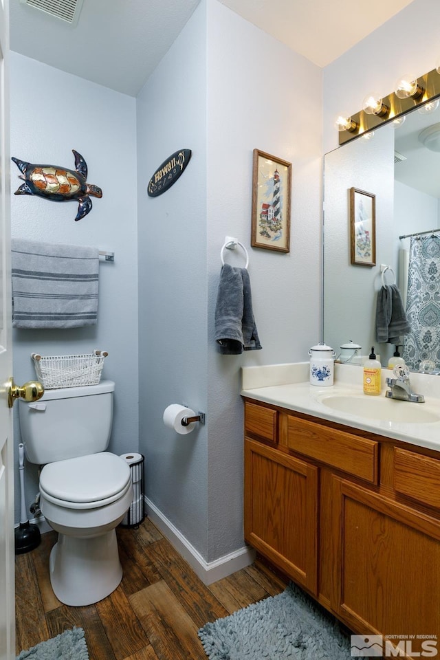 full bath with visible vents, baseboards, toilet, wood finished floors, and vanity