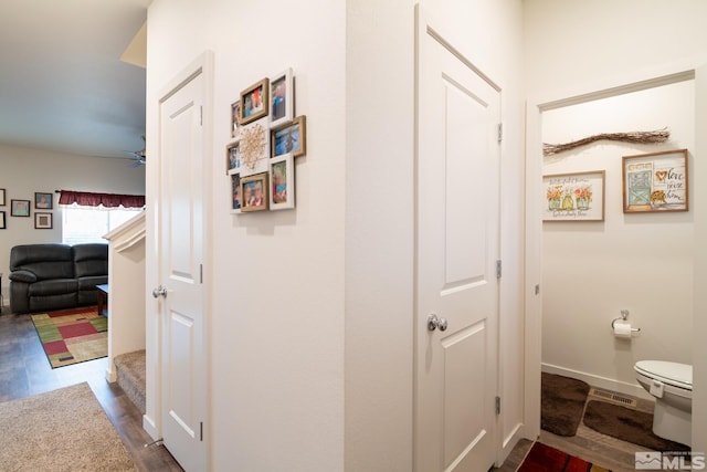 corridor with visible vents, baseboards, and dark wood-type flooring