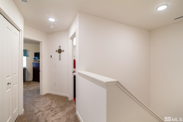 hall featuring recessed lighting, an upstairs landing, visible vents, baseboards, and light colored carpet