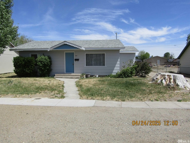 view of front of home featuring a front yard and a shingled roof