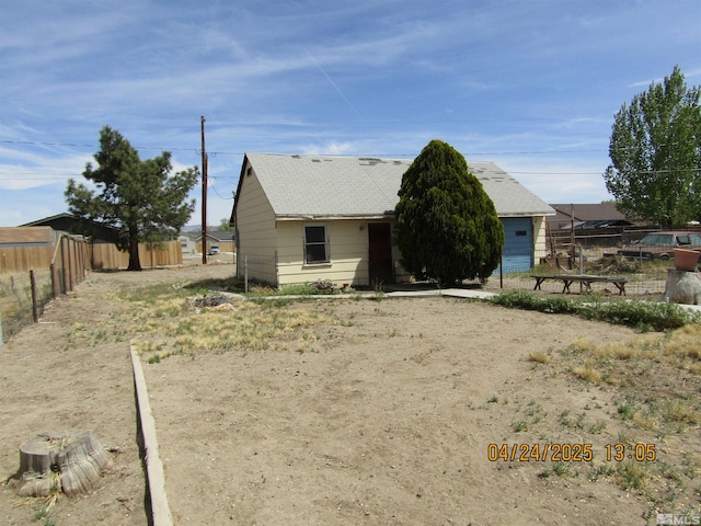 rear view of house featuring a shingled roof and fence