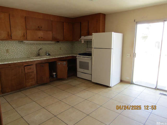 kitchen with light countertops, a sink, under cabinet range hood, and white appliances