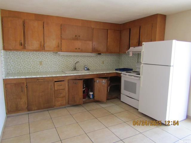 kitchen featuring light countertops, a sink, brown cabinets, and white appliances