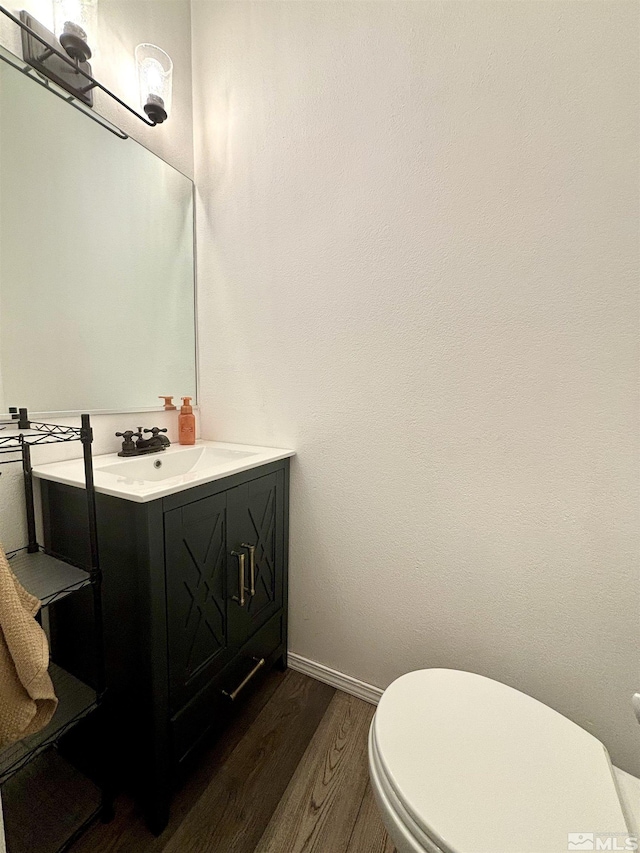 bathroom with baseboards, wood finished floors, toilet, and vanity