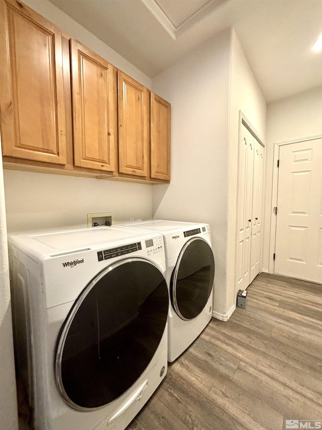 laundry area with wood finished floors, washer and clothes dryer, cabinet space, and baseboards