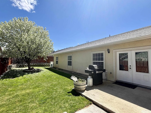 rear view of house with a lawn, a patio area, french doors, and fence
