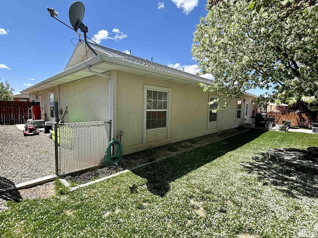 view of side of property featuring stucco siding, fence, and a lawn