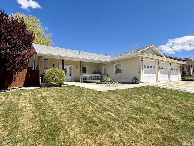 view of front facade with stucco siding, fence, driveway, a front yard, and an attached garage