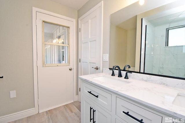 bathroom featuring baseboards, wood finished floors, a shower, and vanity