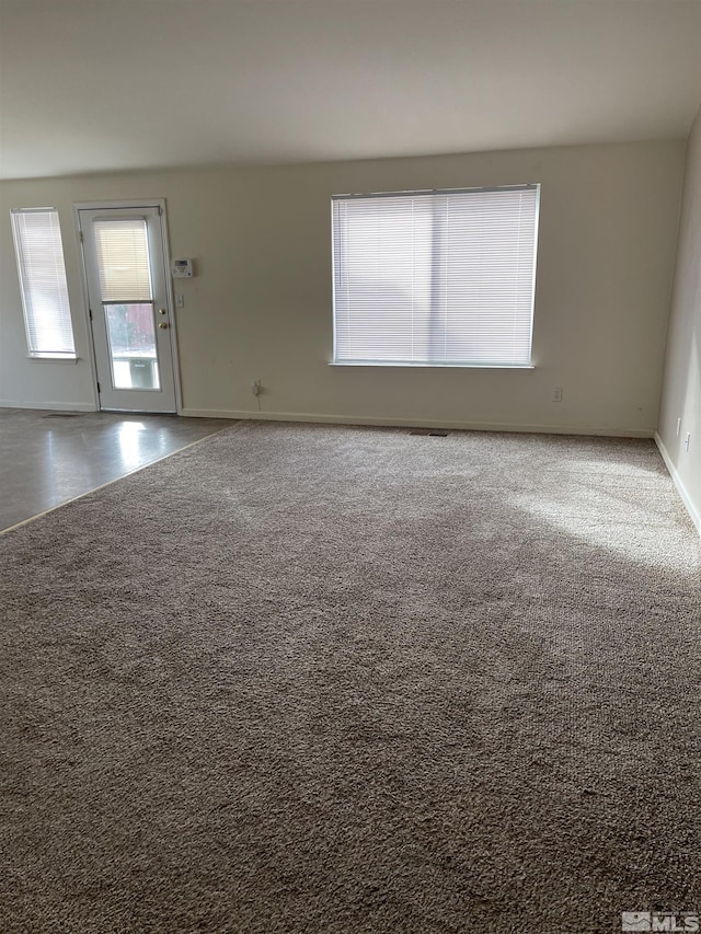 empty room featuring carpet, visible vents, and baseboards