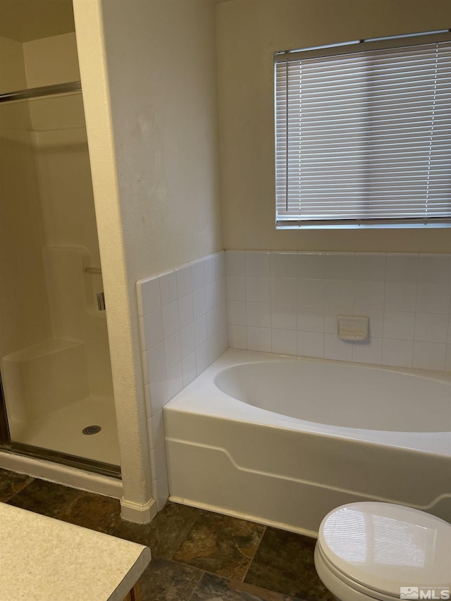 full bath featuring stone finish flooring, a stall shower, toilet, and a bath