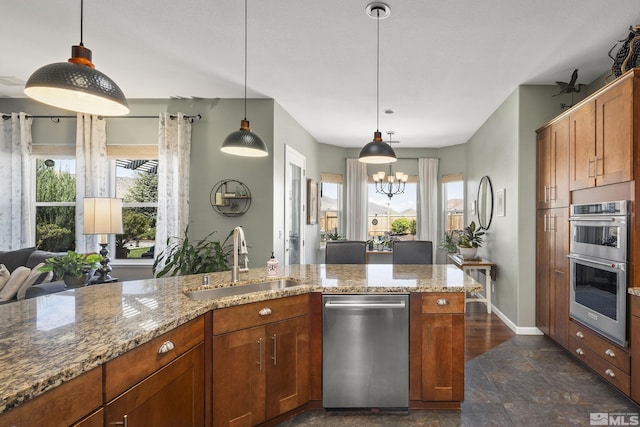 kitchen with a sink, appliances with stainless steel finishes, a healthy amount of sunlight, and light stone countertops