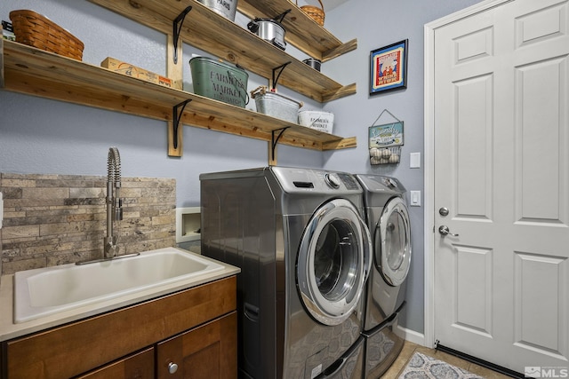 washroom featuring washing machine and clothes dryer, baseboards, and a sink