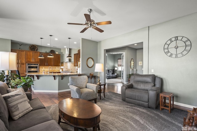 living area featuring a ceiling fan, baseboards, recessed lighting, and dark wood-type flooring