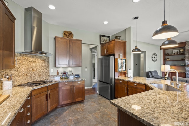 kitchen featuring light stone counters, a sink, wall chimney exhaust hood, and appliances with stainless steel finishes