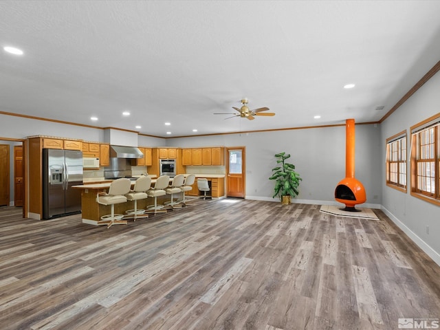 living area with ceiling fan, recessed lighting, baseboards, wood finished floors, and ornamental molding