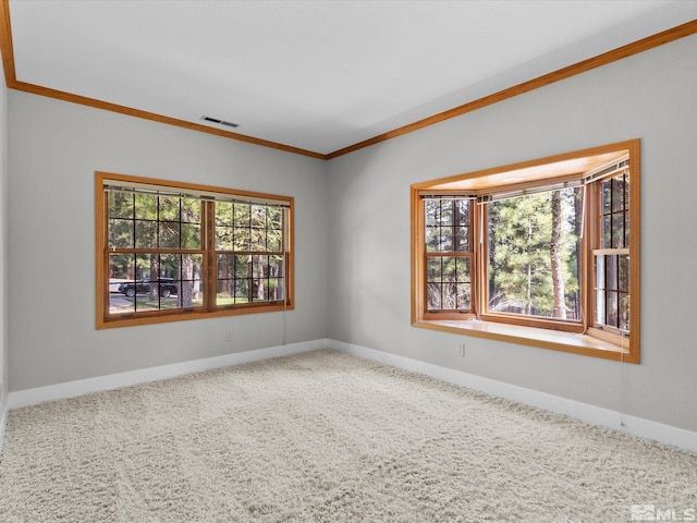 carpeted spare room with crown molding, baseboards, and visible vents