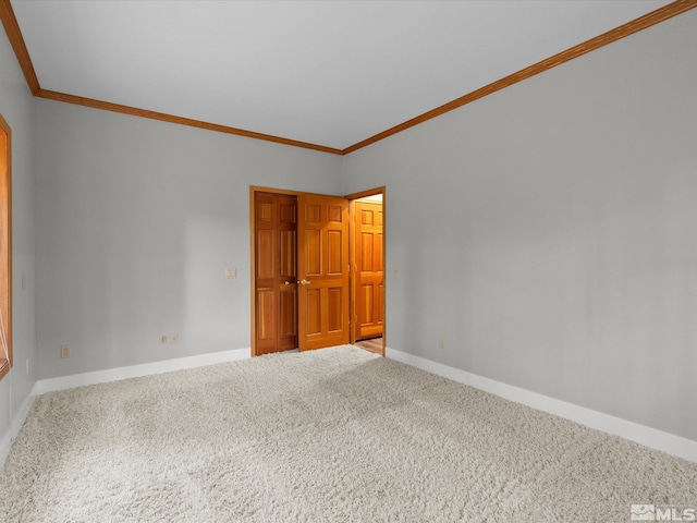empty room featuring carpet floors, ornamental molding, and baseboards