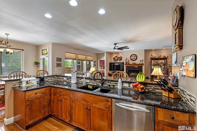 kitchen featuring a sink, light wood finished floors, dishwasher, ceiling fan with notable chandelier, and a healthy amount of sunlight