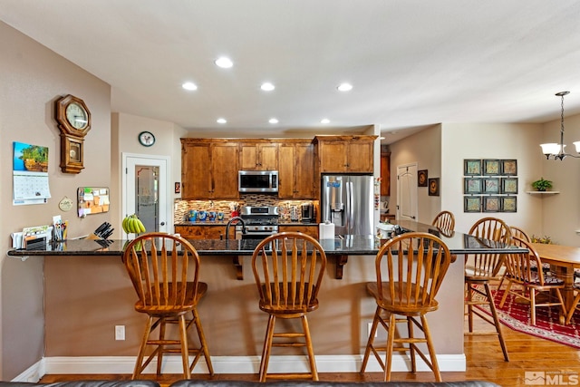 kitchen with stainless steel appliances, recessed lighting, wood finished floors, and a kitchen bar