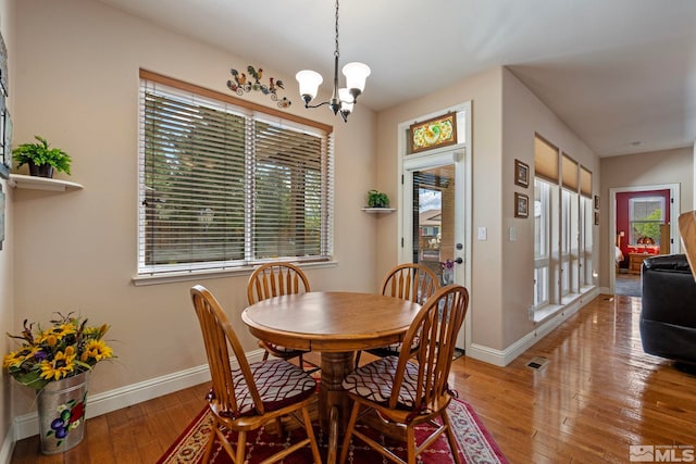 dining space with visible vents, baseboards, an inviting chandelier, and light wood-type flooring
