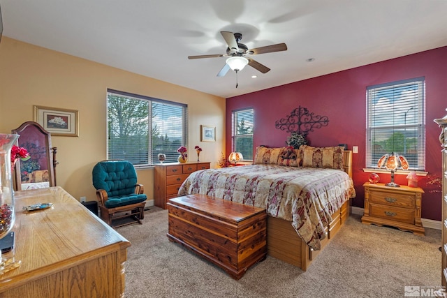 bedroom featuring a ceiling fan, light colored carpet, and multiple windows
