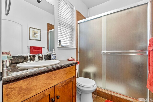 bathroom with vanity, tile patterned flooring, a stall shower, and toilet