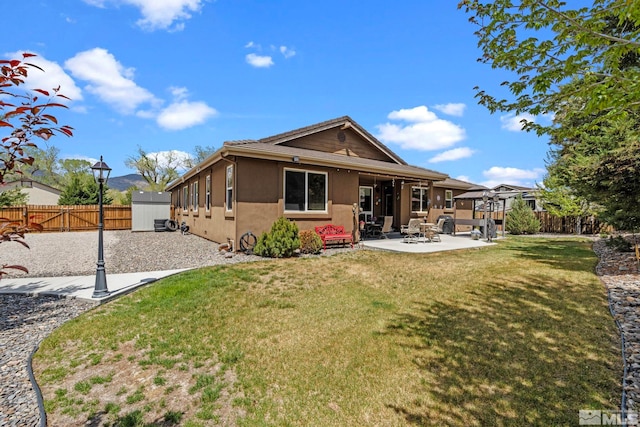 back of house featuring a yard, a fenced backyard, a patio area, and stucco siding