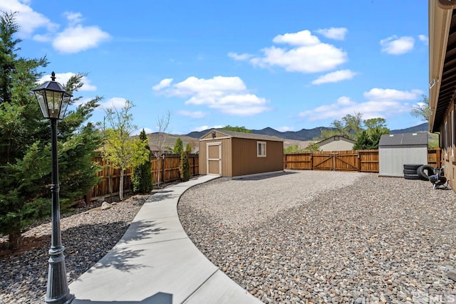exterior space with a mountain view, an outbuilding, a shed, and a fenced backyard