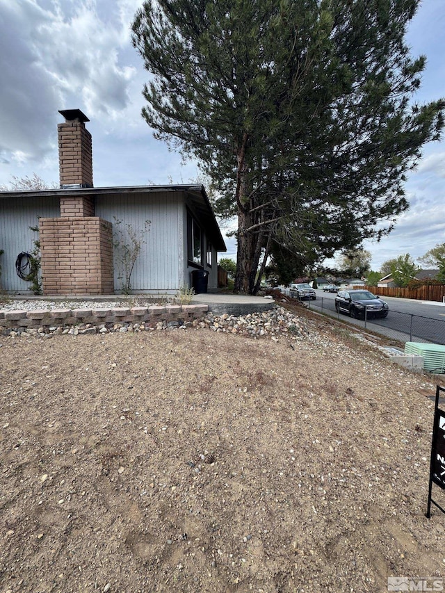 view of side of home featuring fence and a chimney