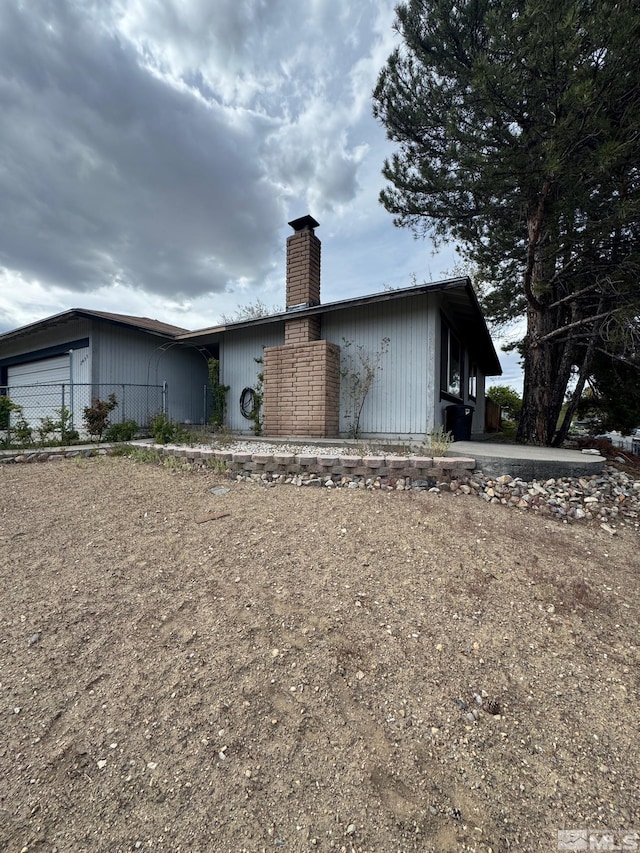 rear view of house with an attached garage and a chimney