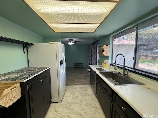 kitchen with white refrigerator with ice dispenser, a sink, dark cabinets, a ceiling fan, and dishwashing machine