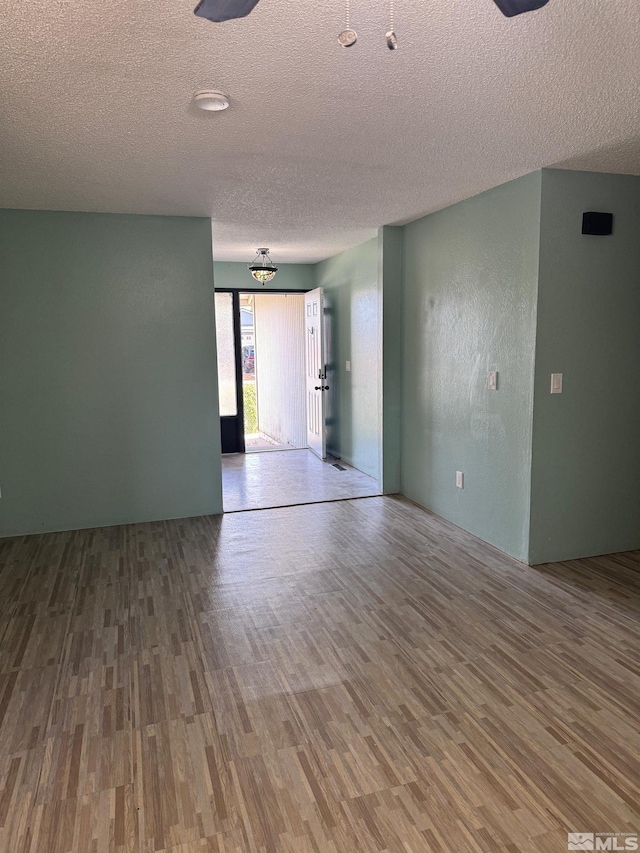 unfurnished room with a textured ceiling and wood finished floors