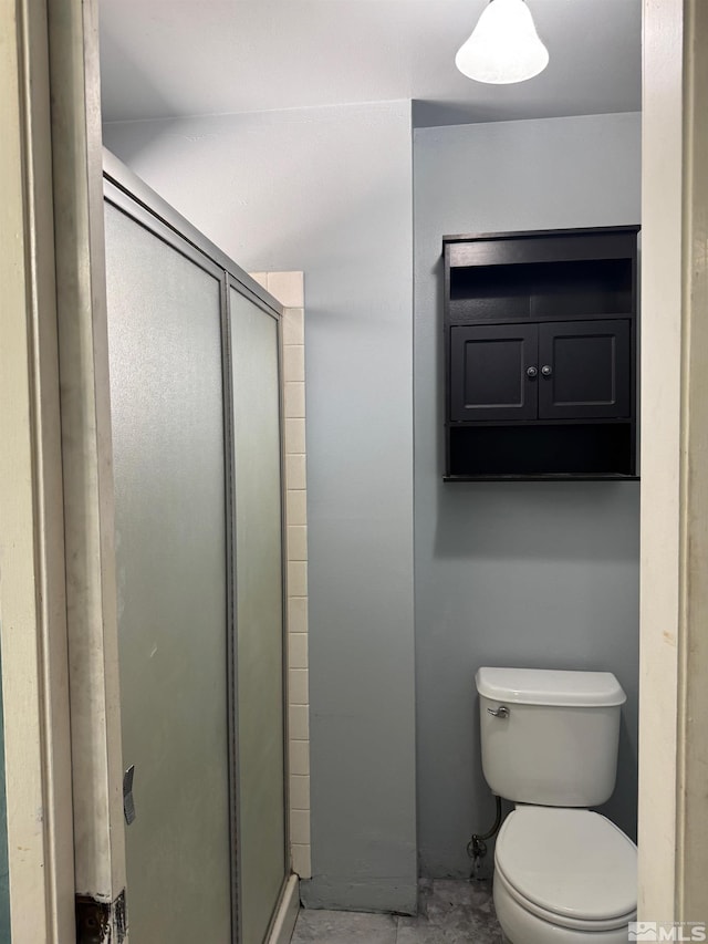 bathroom featuring toilet and a shower stall