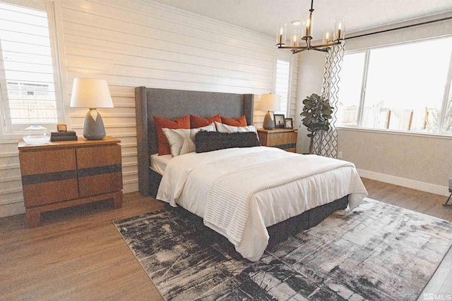bedroom with baseboards, wood finished floors, and a chandelier