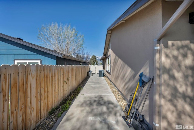 view of home's exterior with stucco siding, central AC unit, and fence