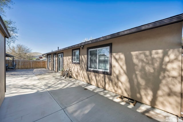 view of home's exterior with fence, a patio, and stucco siding