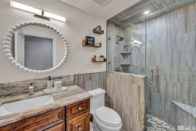 bathroom with visible vents, vanity, toilet, tile walls, and a stall shower