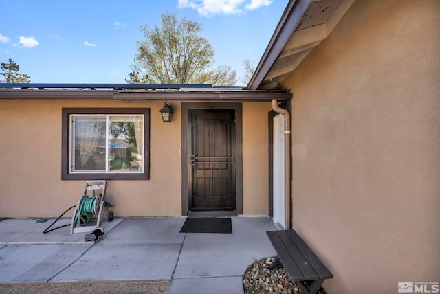 entrance to property with a patio and stucco siding