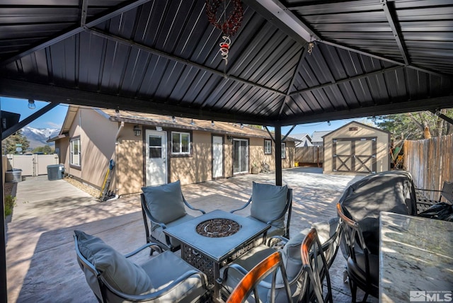 view of patio featuring a fenced backyard, a fire pit, a storage shed, and an outbuilding