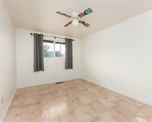 empty room with baseboards, a ceiling fan, and visible vents