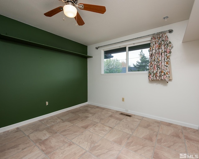 empty room with baseboards, ceiling fan, and visible vents