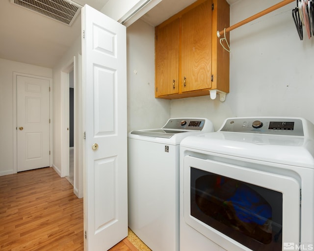 washroom featuring light wood-style floors, washer and dryer, cabinet space, and visible vents