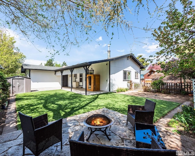 rear view of house featuring a yard, a patio, a shed, and an outdoor fire pit