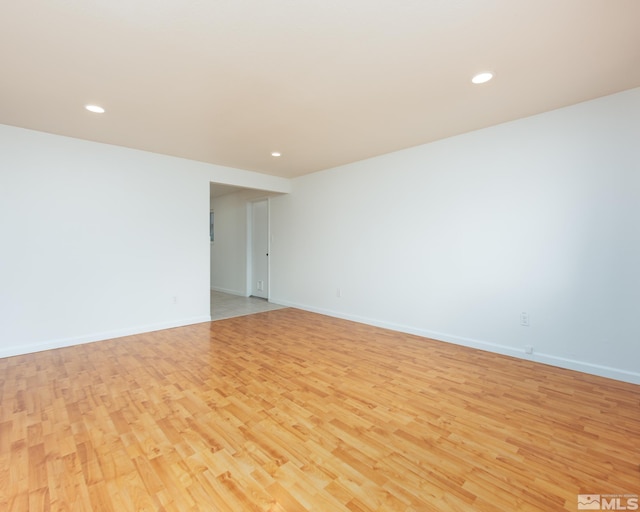 empty room featuring recessed lighting, baseboards, and light wood-type flooring