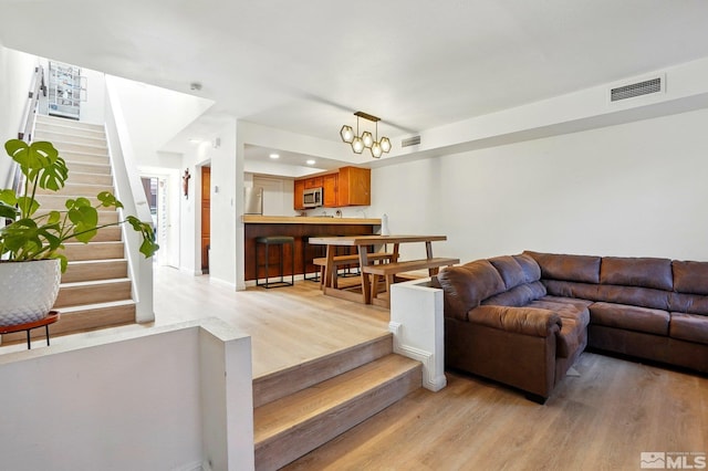 living area with visible vents, light wood-style flooring, and stairway