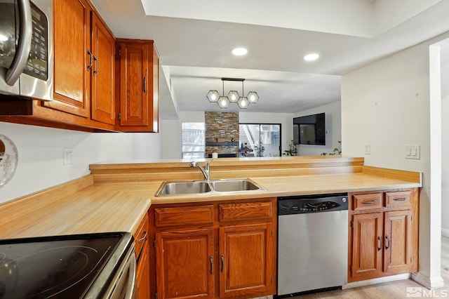 kitchen with light countertops, brown cabinets, appliances with stainless steel finishes, and a sink