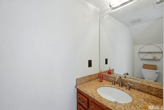 bathroom featuring toilet, visible vents, lofted ceiling, and vanity